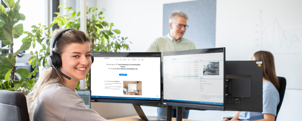 Junge Frau arbeitet mit dem Business Filemanager Testaccount und blickt über ihre Schulter den Betrachter an